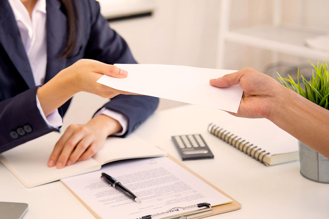 A close-up image of a person handing a paper to another person