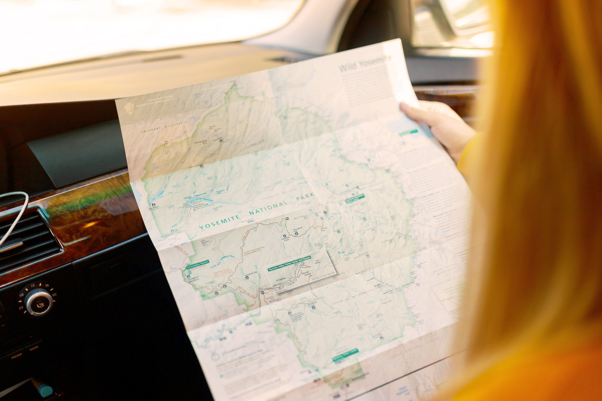 A close-up image of a person holding a map while in the car