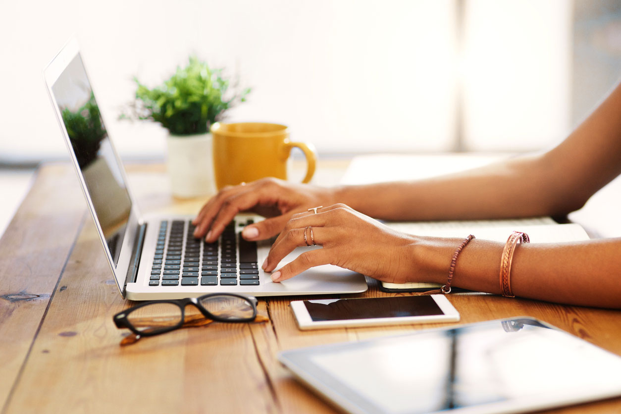 A woman's hands type on a laptop keyboard