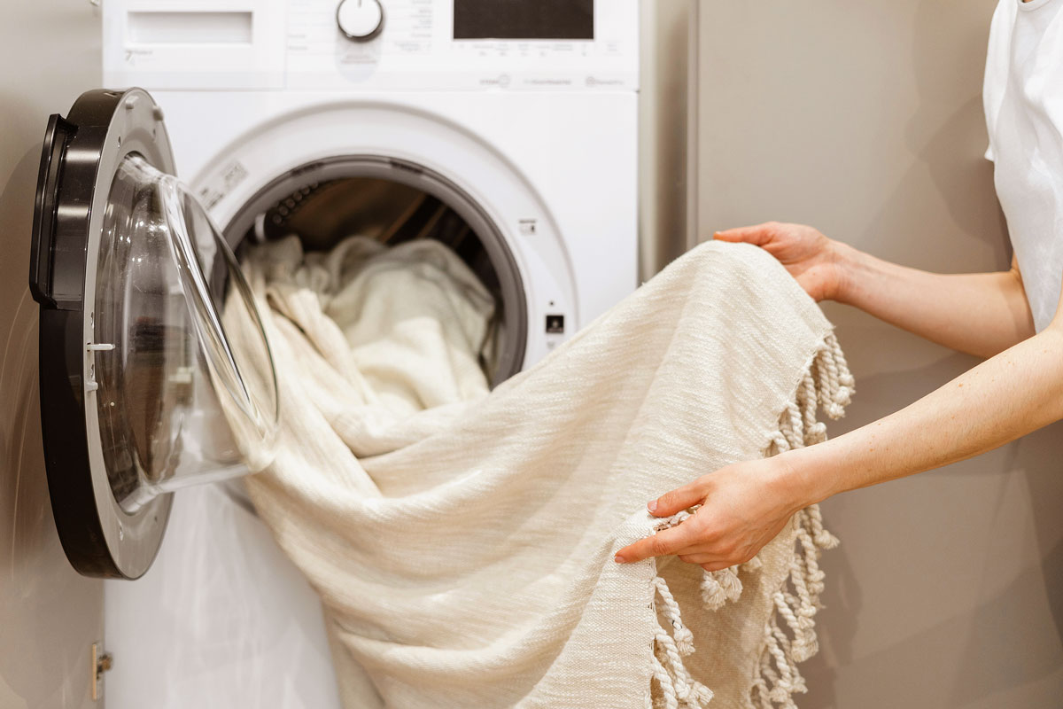 An image of a person taking a white blanket out of the dryer