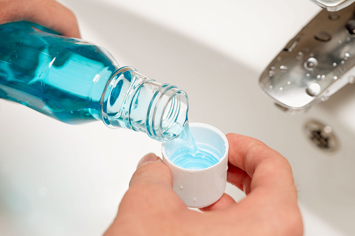 An image of mouthwash being poured into a cap