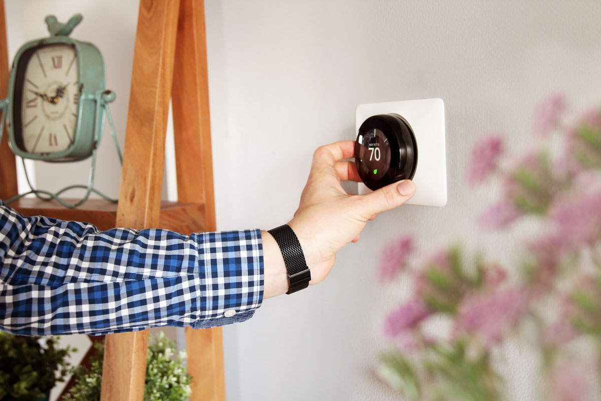 An image of a hand adjusting a thermostat