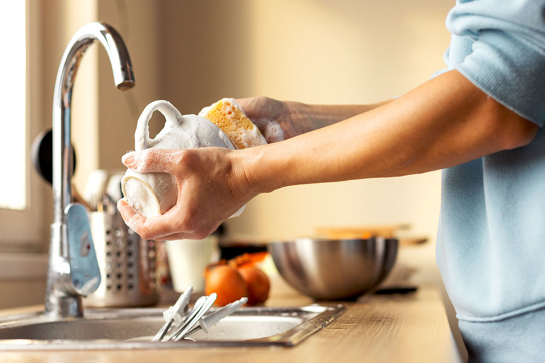 An image of a person cleaning a coffee mug with a sponge