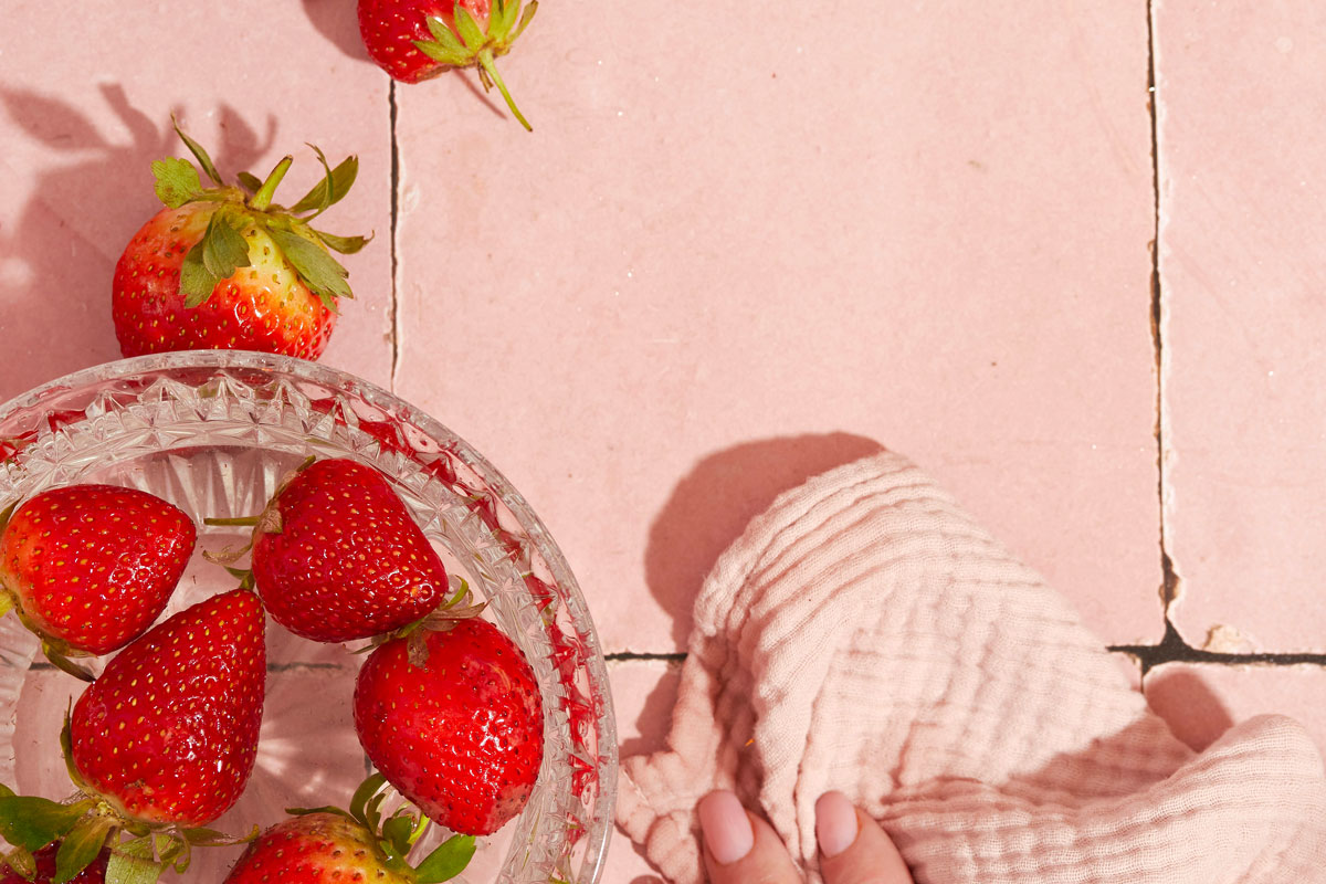 An image of a bowl of strawberries on pink tile