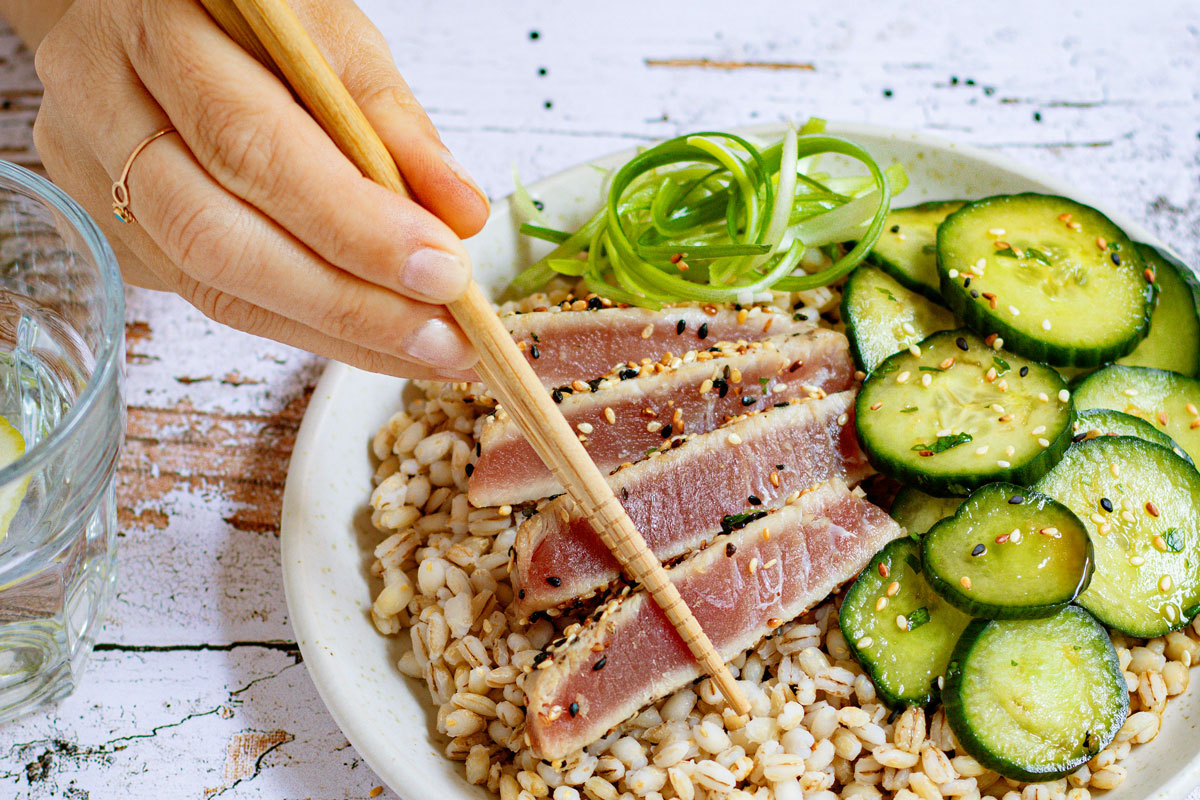 An image of a bowl of brown rice, tuna, and cucumbers