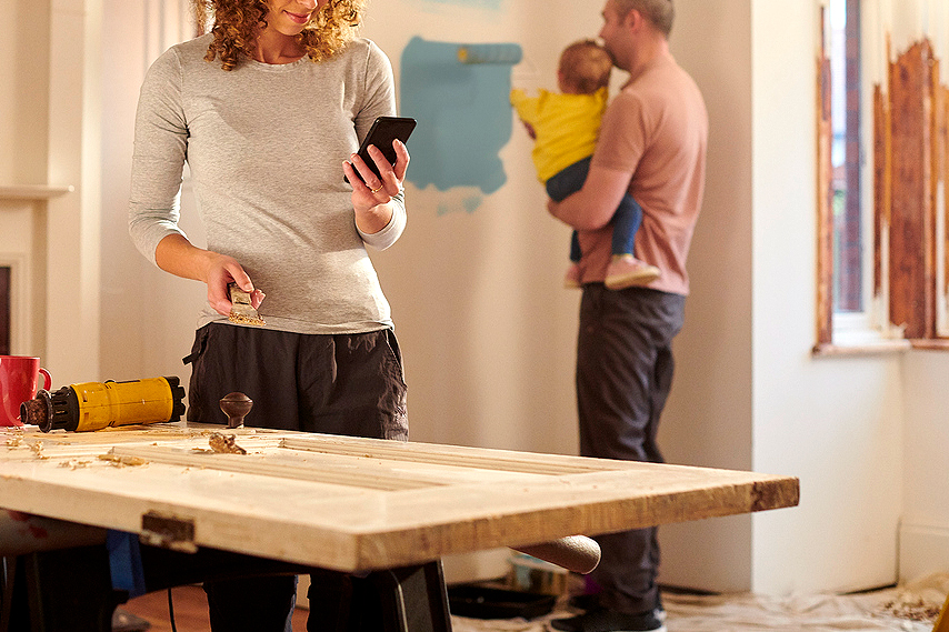 An image of a woman looking at her phone in a room that is being renovated.