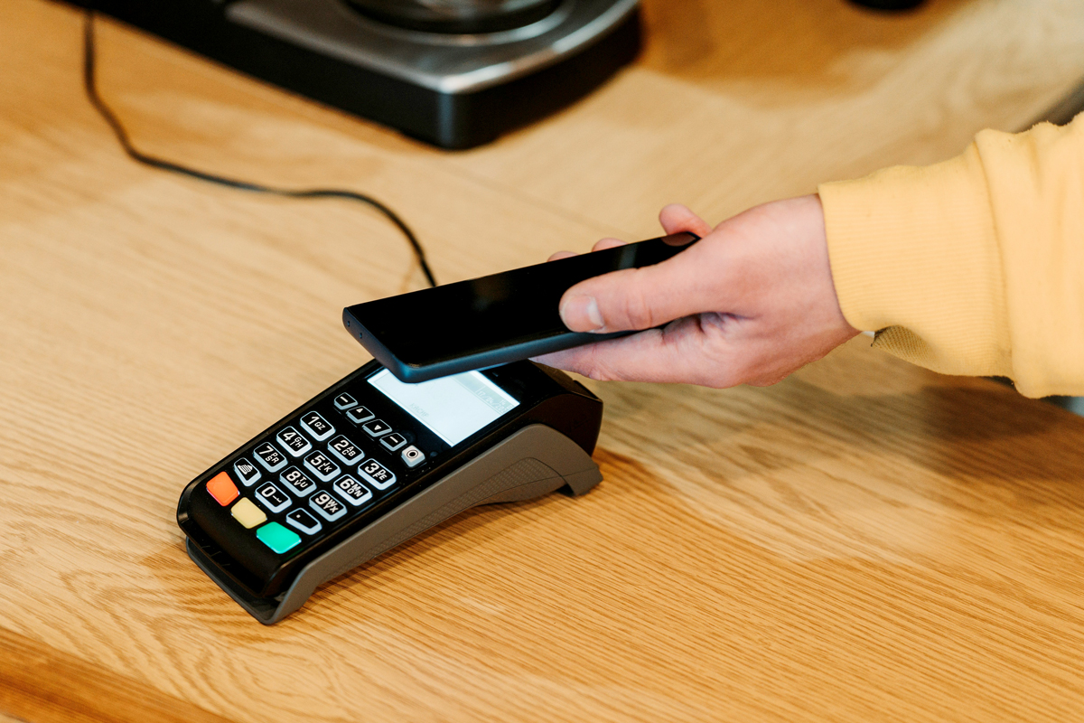 An image of a person holding their pone to a credit card machine