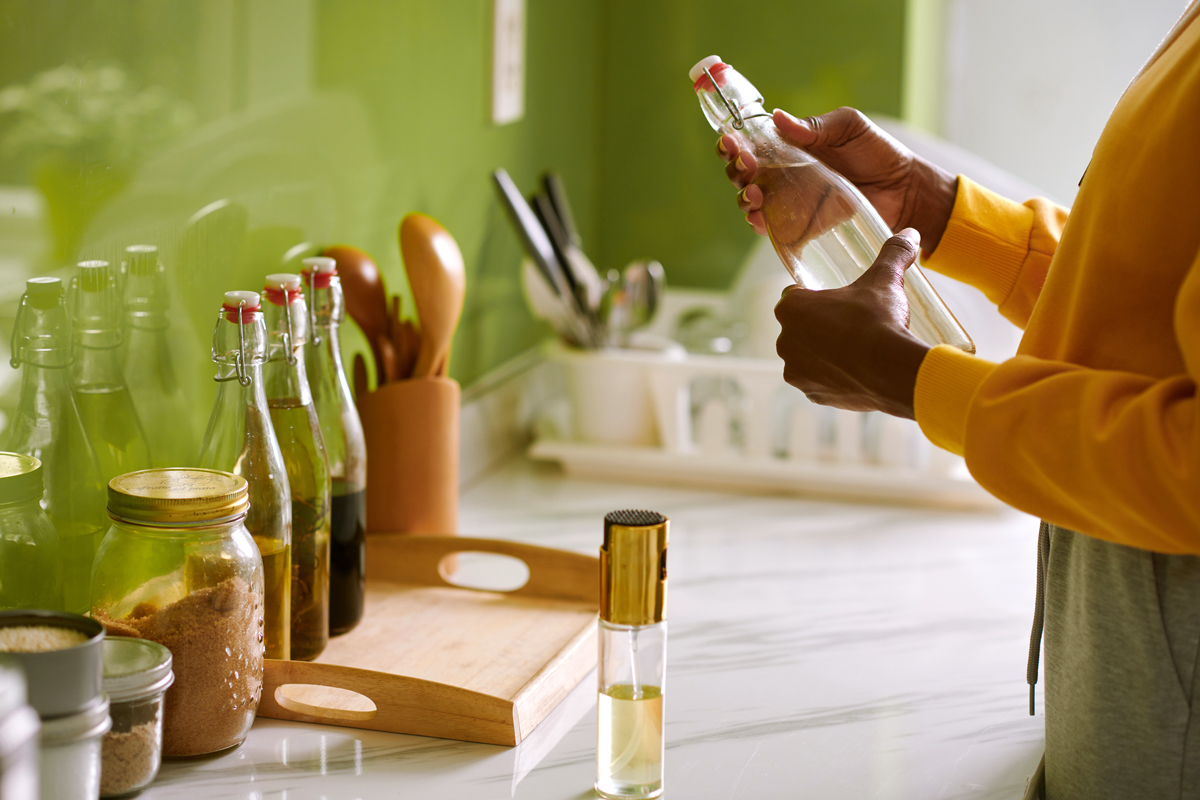 An image of a woman in a kitchen holding a clear bottle 
