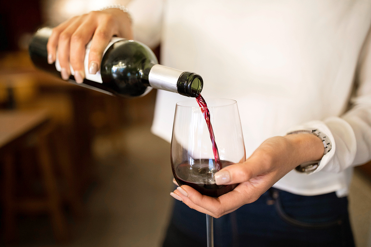An image of a woman pouring a glass of red wine