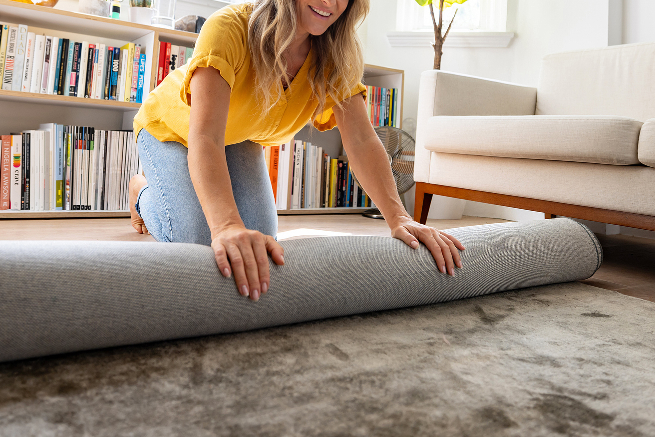 An image of a woman rolling a gray rug