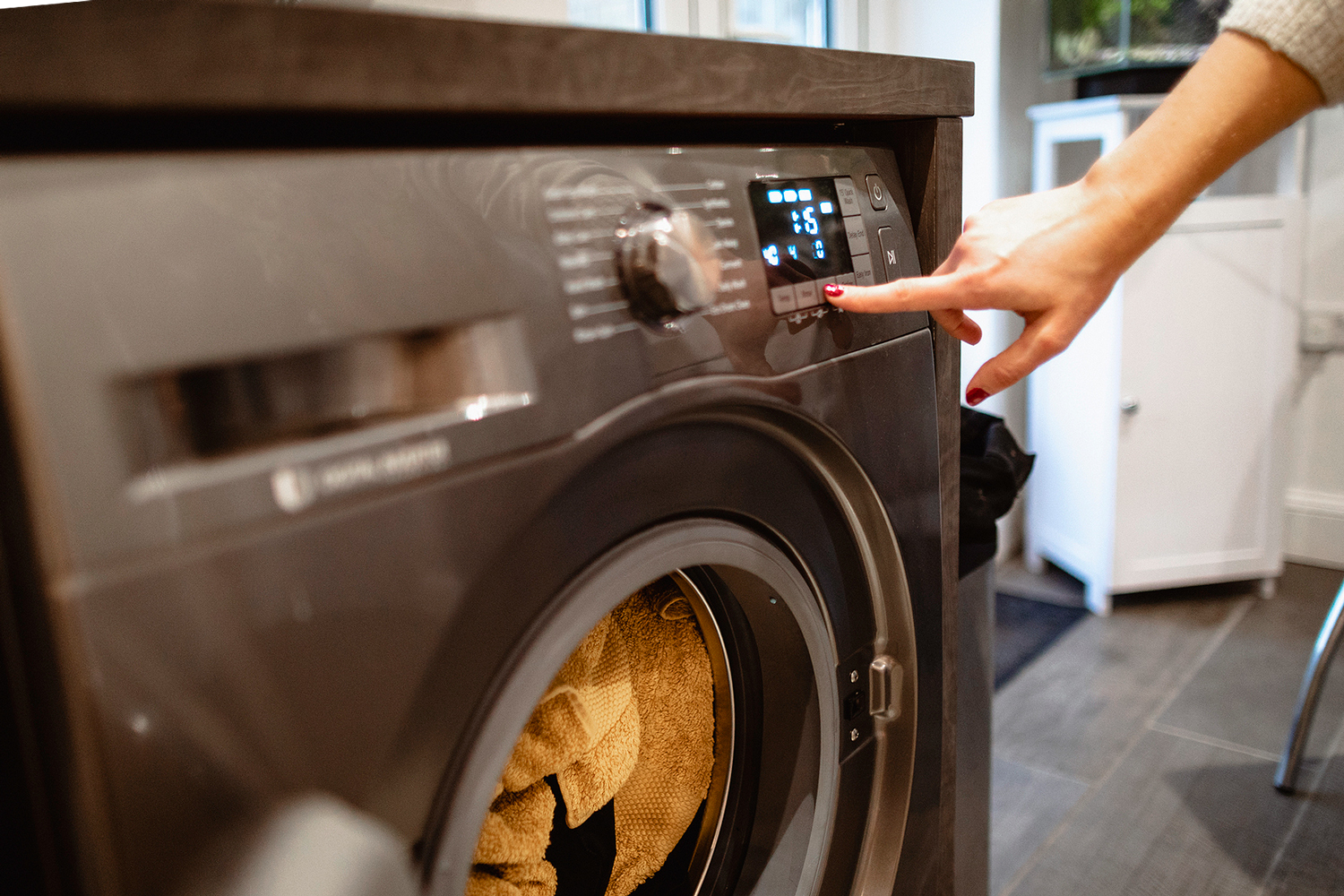 An image of a woman pressing a button on a dryer