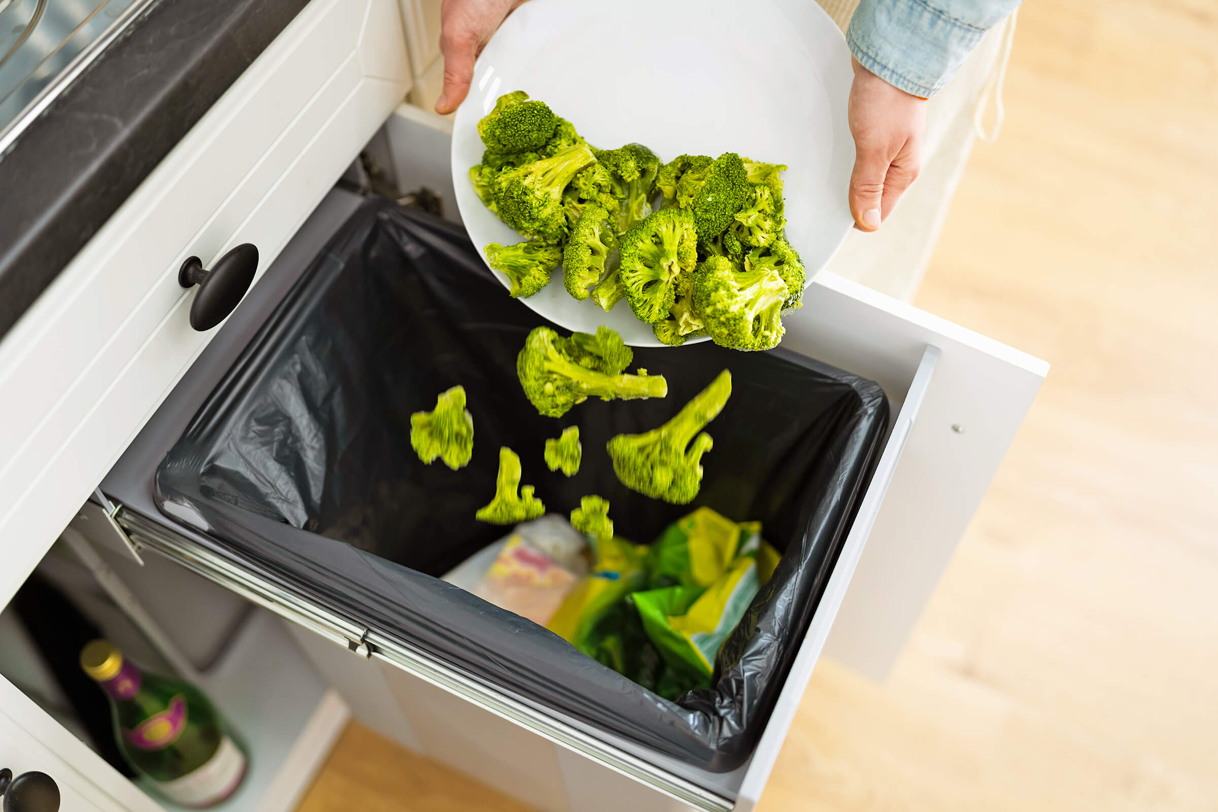 Broccoli being thrown in the trash