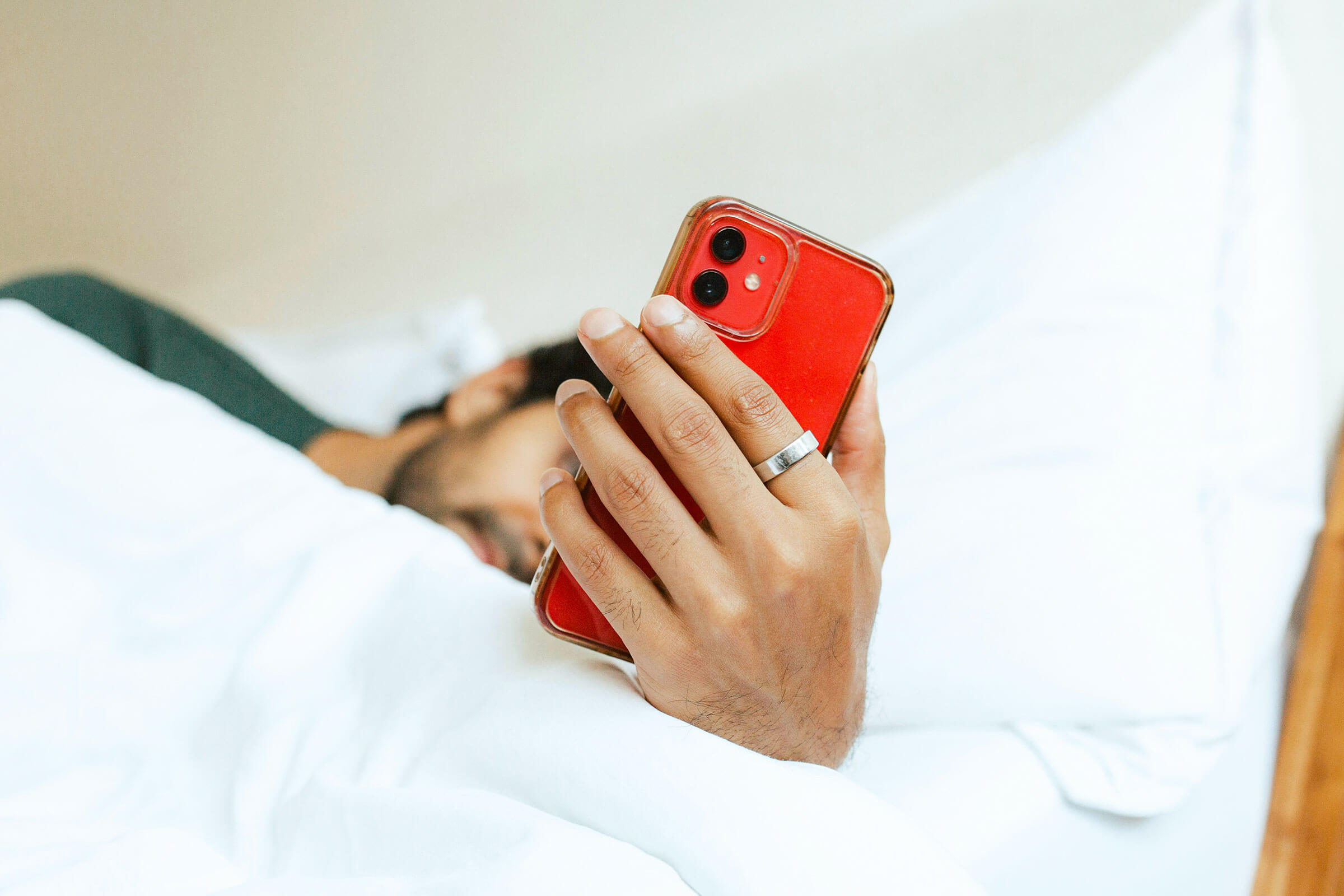 Man in bed looking at his phone