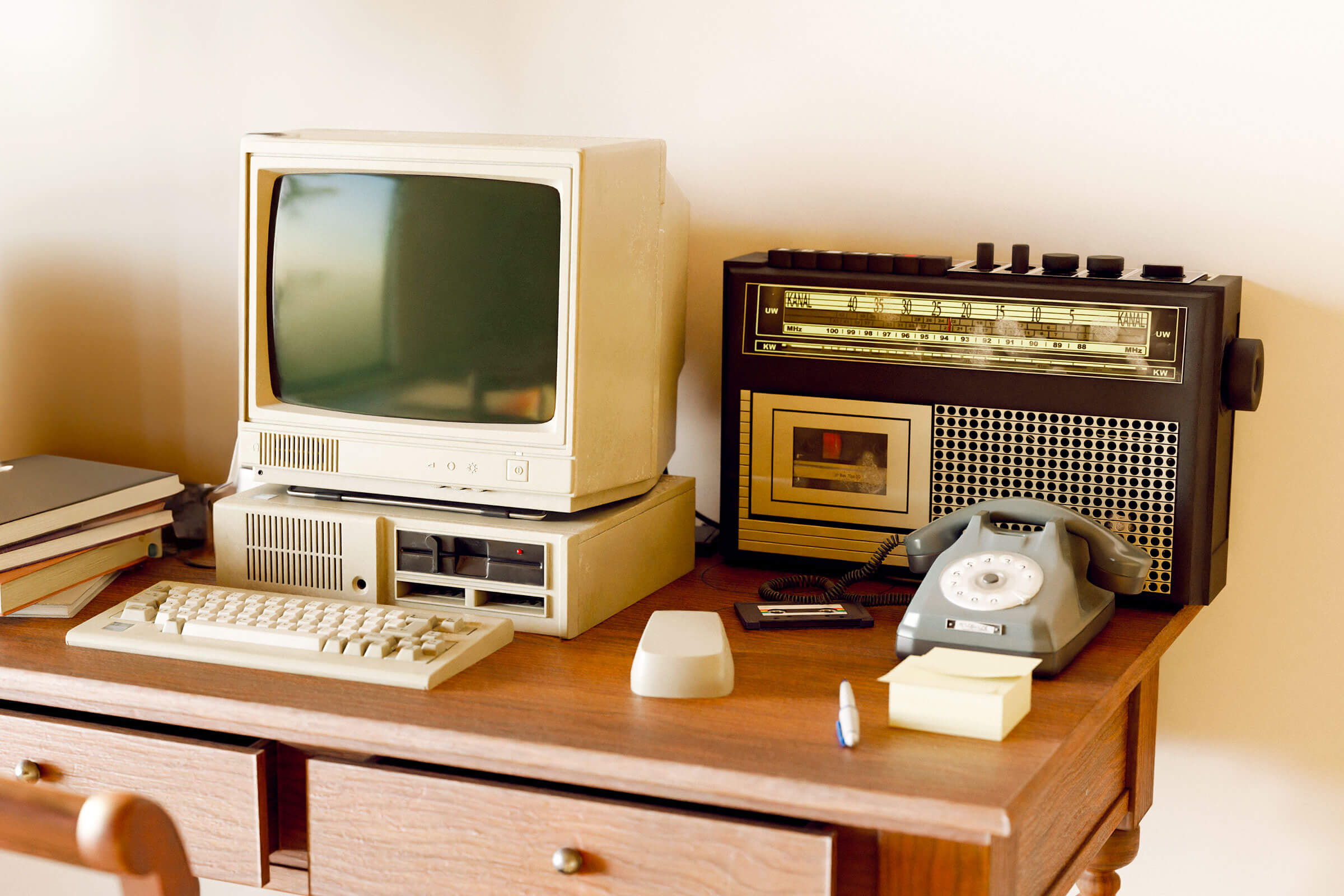 Desk with a vintage computer, vintage radio, and vintage telephone on it