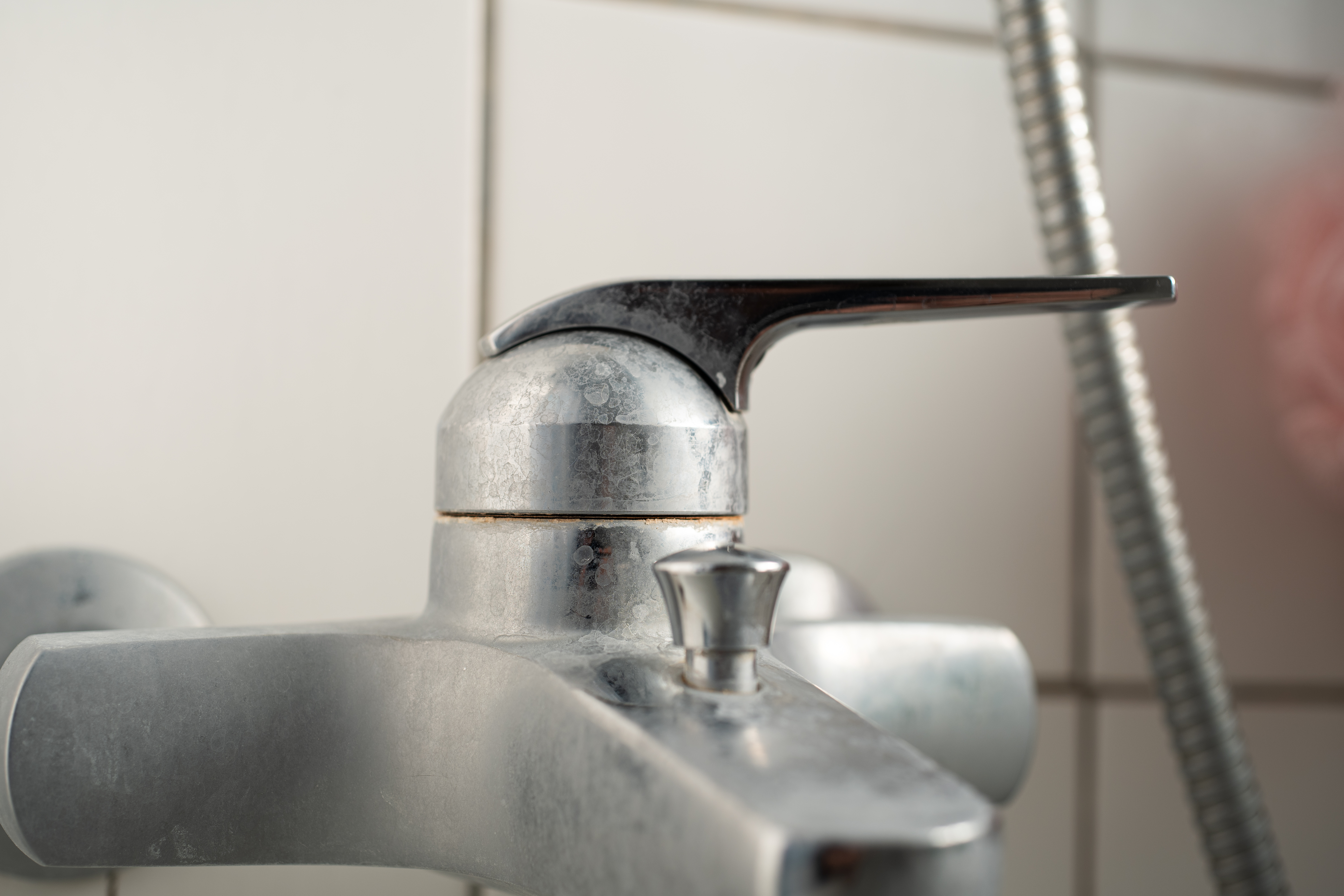 Old lime scale or calcium stained bathtub faucet from hard water. Close up detail shot, shallow depth of field, no people.