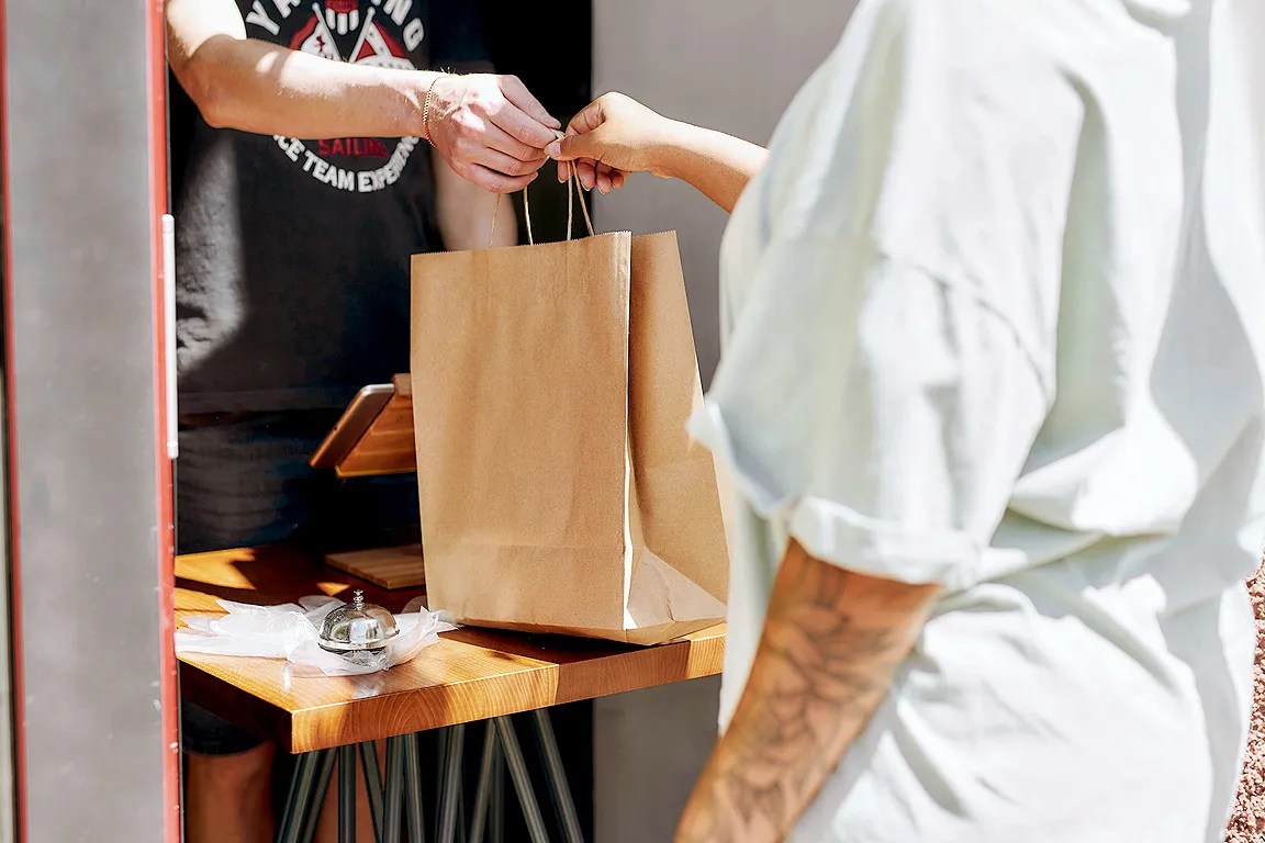 Person being handed a take-out bag of food
