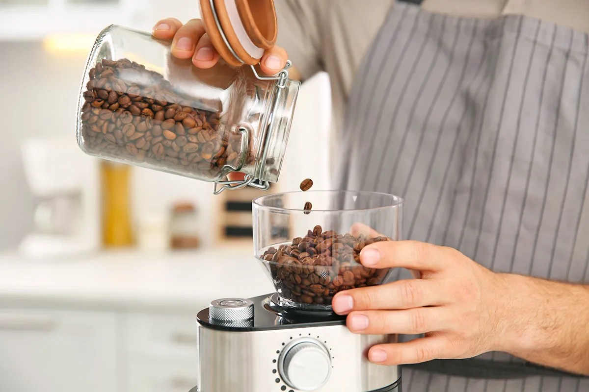 Man using electric coffee grinder in kitchen