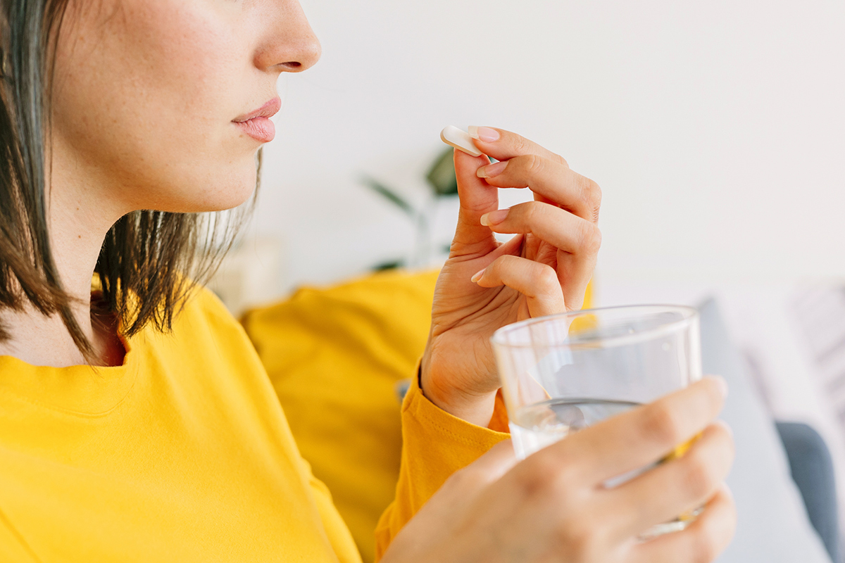 Close-up of woman taking a pill with water
