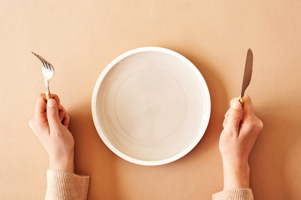 Hands with knife and fork and empty plate