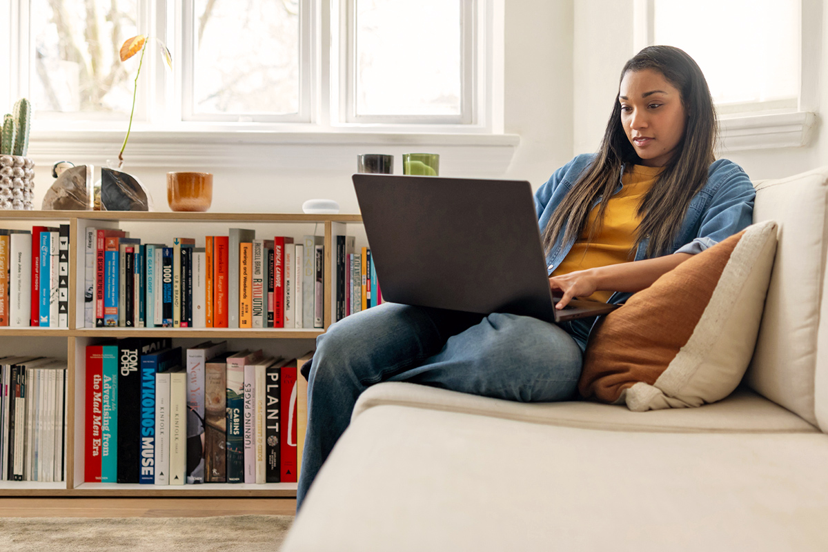 Woman on a laptop next to a bookshelf