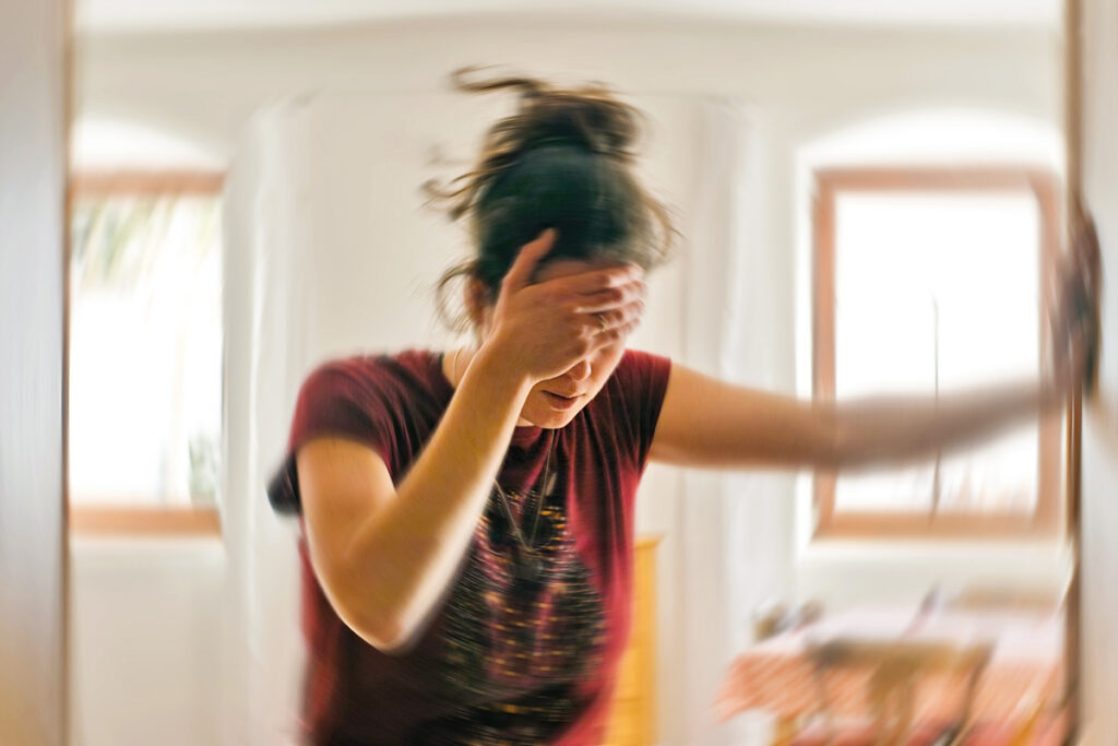 Woman with hand to head holding wall