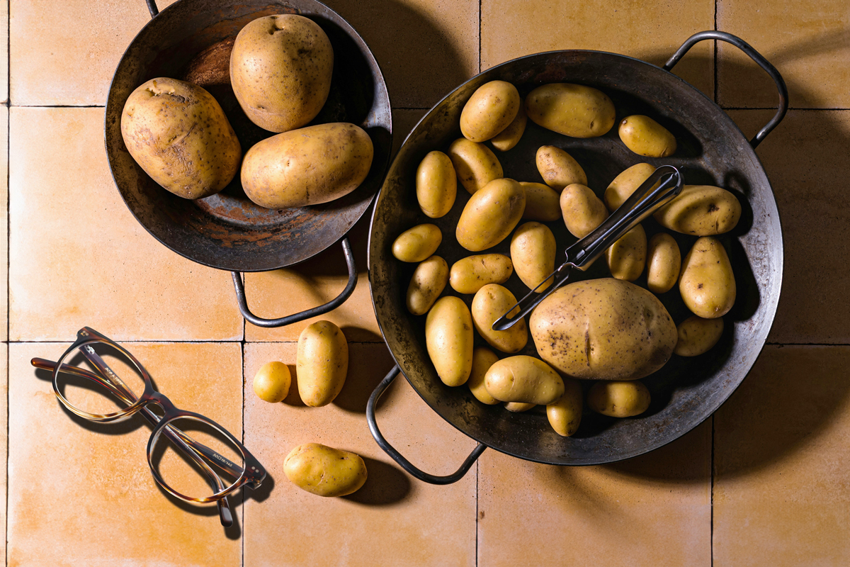 Two pans of potatoes next to a pair of glasses 