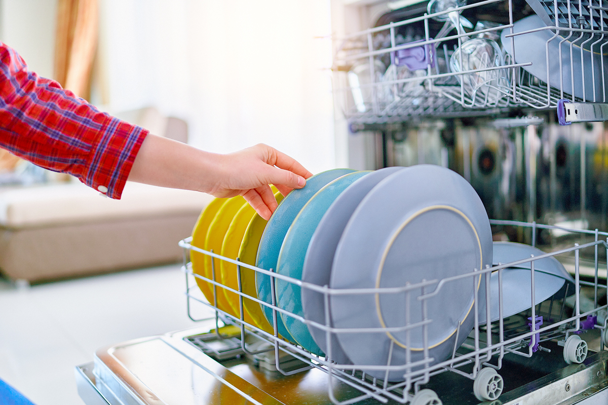 Person loading a dishwasher with plates 