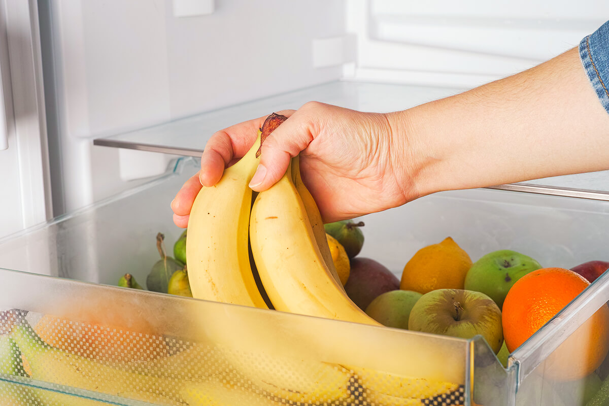 Person putting bananas in the fridge 