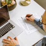 Person in front of computer with paper and pencil