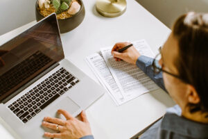 Person in front of computer with paper and pencil