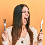 Angry woman holding knife and fork