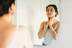 Woman looking in mirror putting on skin care