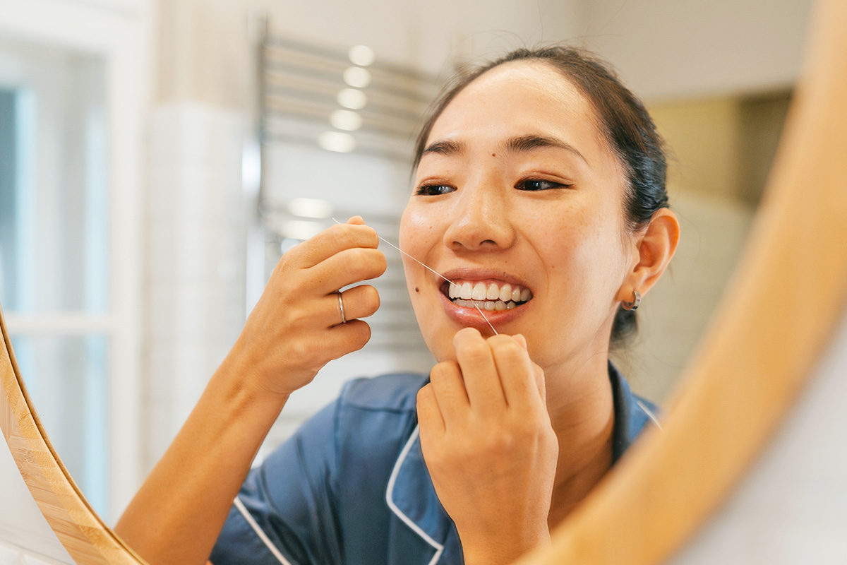 Woman using dental floss as part of her oral hygiene routine