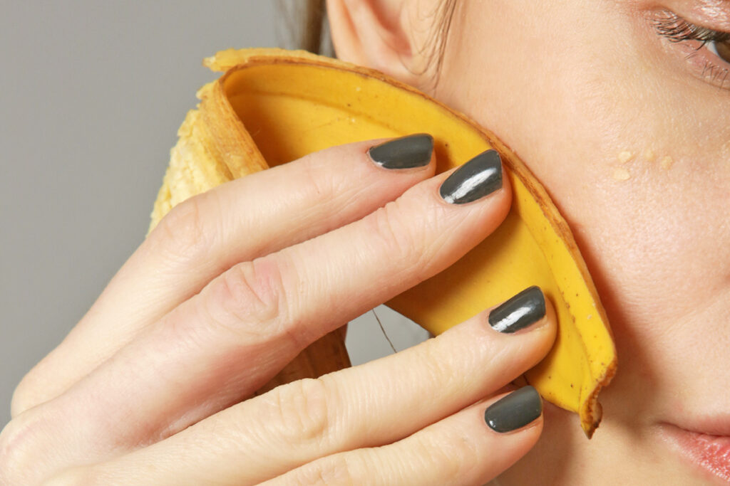 Woman rubbing banana peel on face