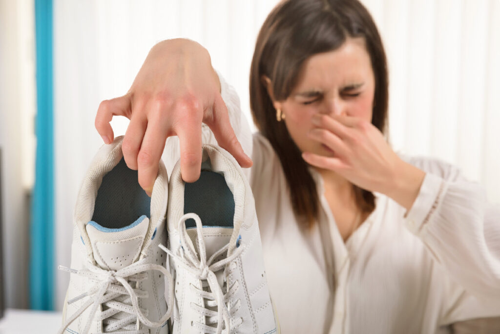 Woman holding shoes, pinching her nose