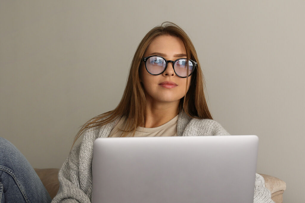 Woman wearing glasses holding laptop