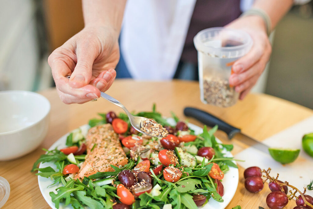 Person adding seeds to salad