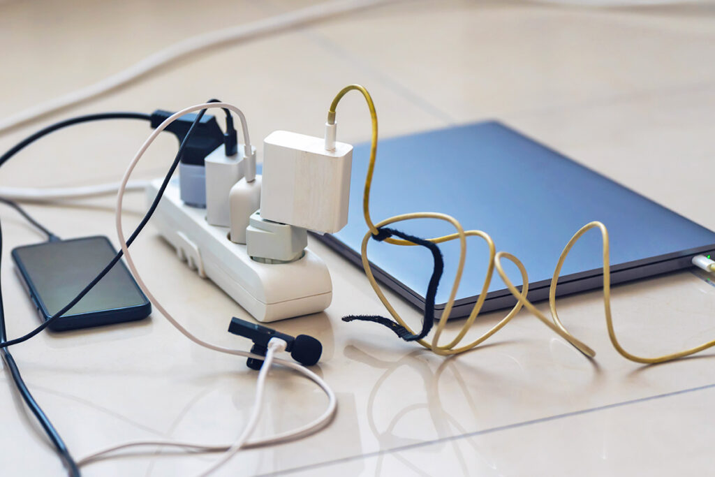 Laptop, phone, and other small items plugged into a power strip