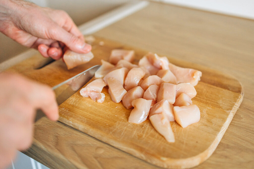 Cutting raw chicken on a cutting board