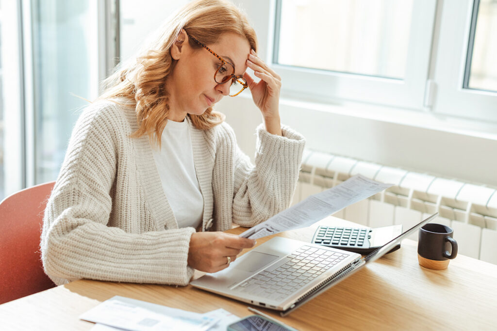 Woman rubbing her forehead looking at bill
