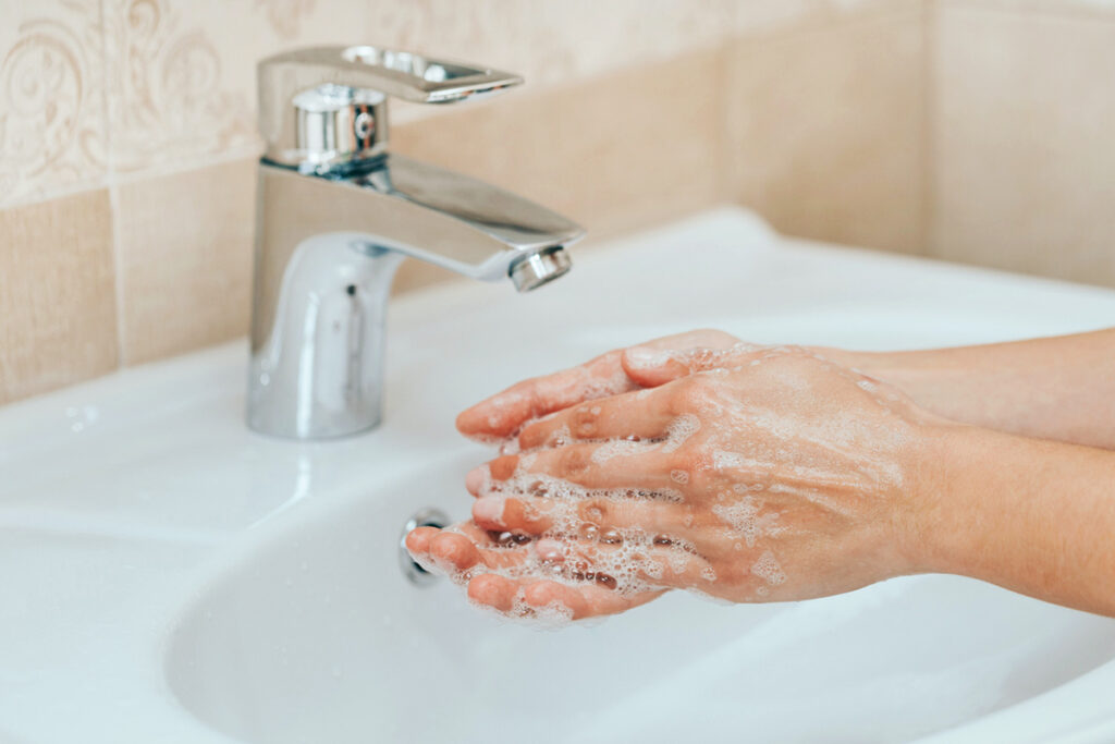 Washing hands with soap and water at a sink