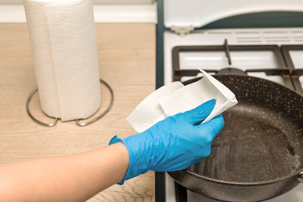 Person holding paper towel over oily pan