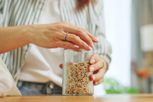 Person putting lid on a jar of grains