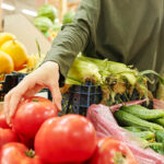Person grabbing tomato at supermarket