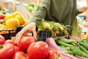 Person grabbing tomato at supermarket