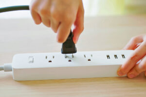 Person plugging a cord into a power strip