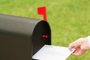 Person putting a letter in a mailbox