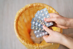 Person holding medication over trash