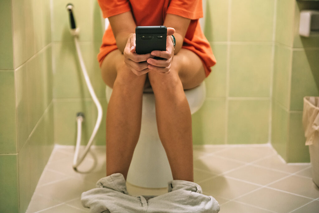 Person on toilet using phone