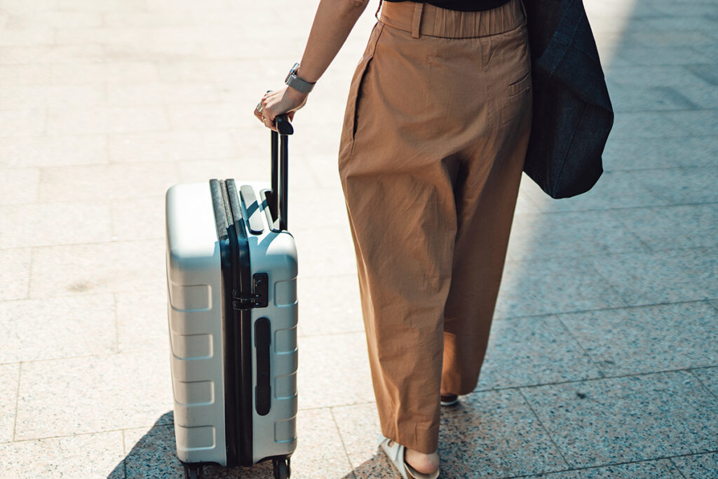 Woman in loose-fitting pants with suitcase